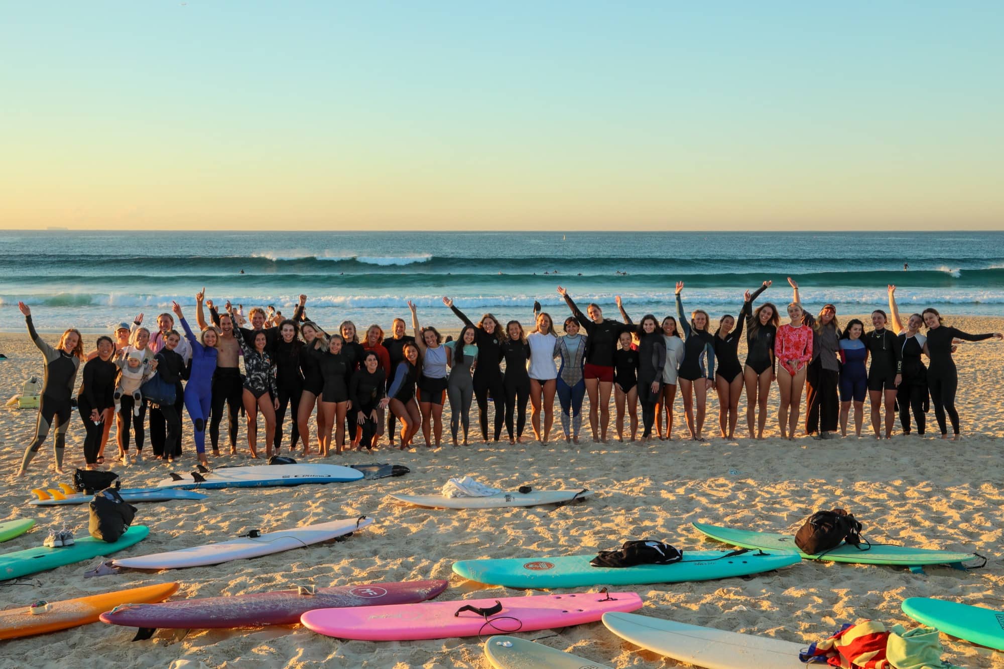 The Bondi Surf Sisters crew celebrating on the beach at sunrise